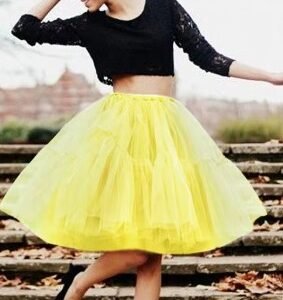 woman wearing yellow colorful evening skirt, black top and black flats, she is dancing on the stairs