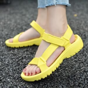 woman wearing yellow sandals and jeans on the grey concrete