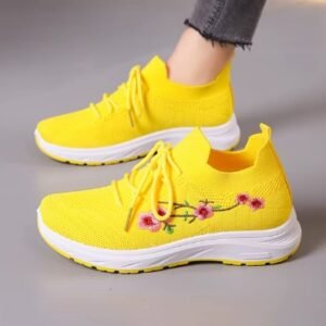 woman wearing one of yellow sneakers women, the other one is next to it, grey background