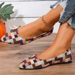 woman wearing colorful checked flats and crossing her legs on the brown floor