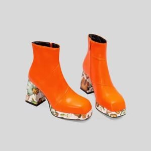 front view of orange colorful Chelsea boots on the grey background