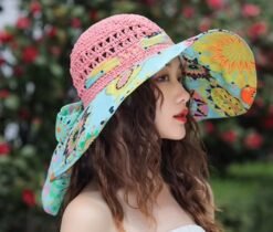 woman with brown hair wearing colorful beach hat, trees in the background