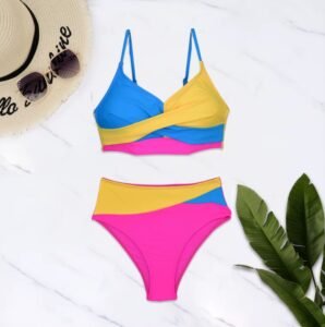 colorful bikini including blue, yellow and pink elements on a white floor, sun hat and a palm next to it