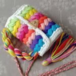 front view of colorful crochet bag lying on the grey surface