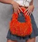 woman wearing grey denim skirt, white top and holding colorful fluffy bag