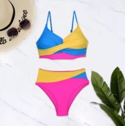 colorful high-waisted bikini on a white floor, palm leves and a beige sun hat next to it