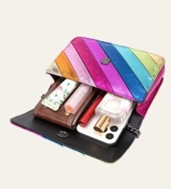 colorful striped bag opened and filled with phone, lip glosses and a wallet