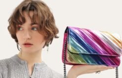 woman with short brown hair holding a colorful striped bag in the air