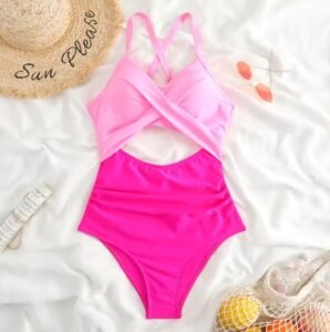 colorful swimsuit in pink tones lying on a white surface, sun hat next to it