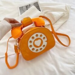 woman holding orange colorful telephone bag above the white bedsheets