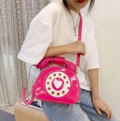 woman wearing jeans, a white shirt and having hot pink colorful telephone bag over her shoulder
