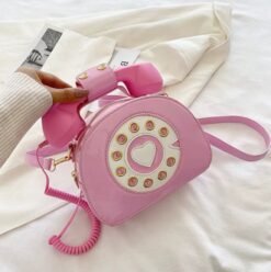 woman holding pink colorful telephone bag above the white bedsheets