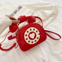 woman holding red colorful telephone bag above the white bedsheets
