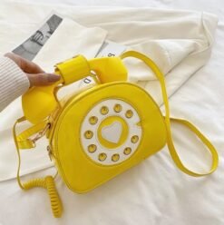 woman holding yellow colorful telephone bag above the white bedsheets