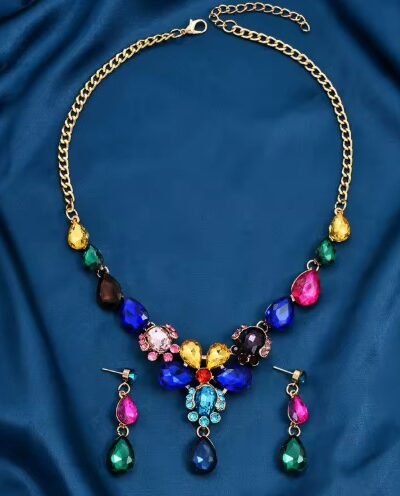 front view of colorful bridal jewelry set arranged on a dark green silky fabric