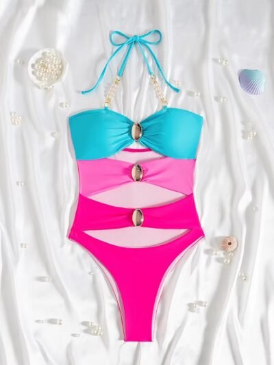 colorful one piece swimsuit with metal rings lying on a white blanket