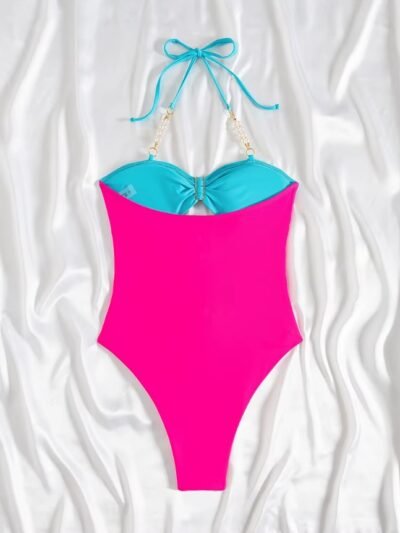 back view of colorful one piece swimsuit with metal rings on a white blanket