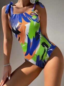 woman posing in vibrant colorful one piece swimsuit in a white room