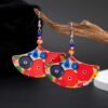 big colorful earrings hung on a branch of a small tree