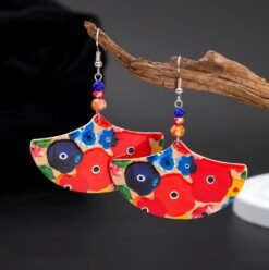 big colorful earrings hung on a branch of a small tree