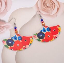 front view of big colorful earrings on a silky, blush pink material