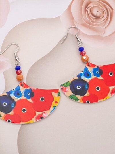 front view of big colorful earrings on a silky, blush pink material