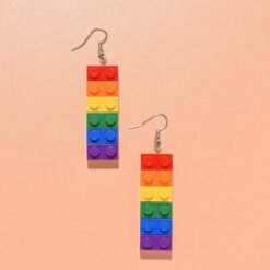 front view of colorful building block earrings placed next to each other on an orange surface
