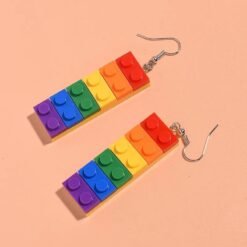 side view of colorful building block earrings on the orange background