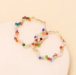 front view of colorful crystal earrings on the beige background