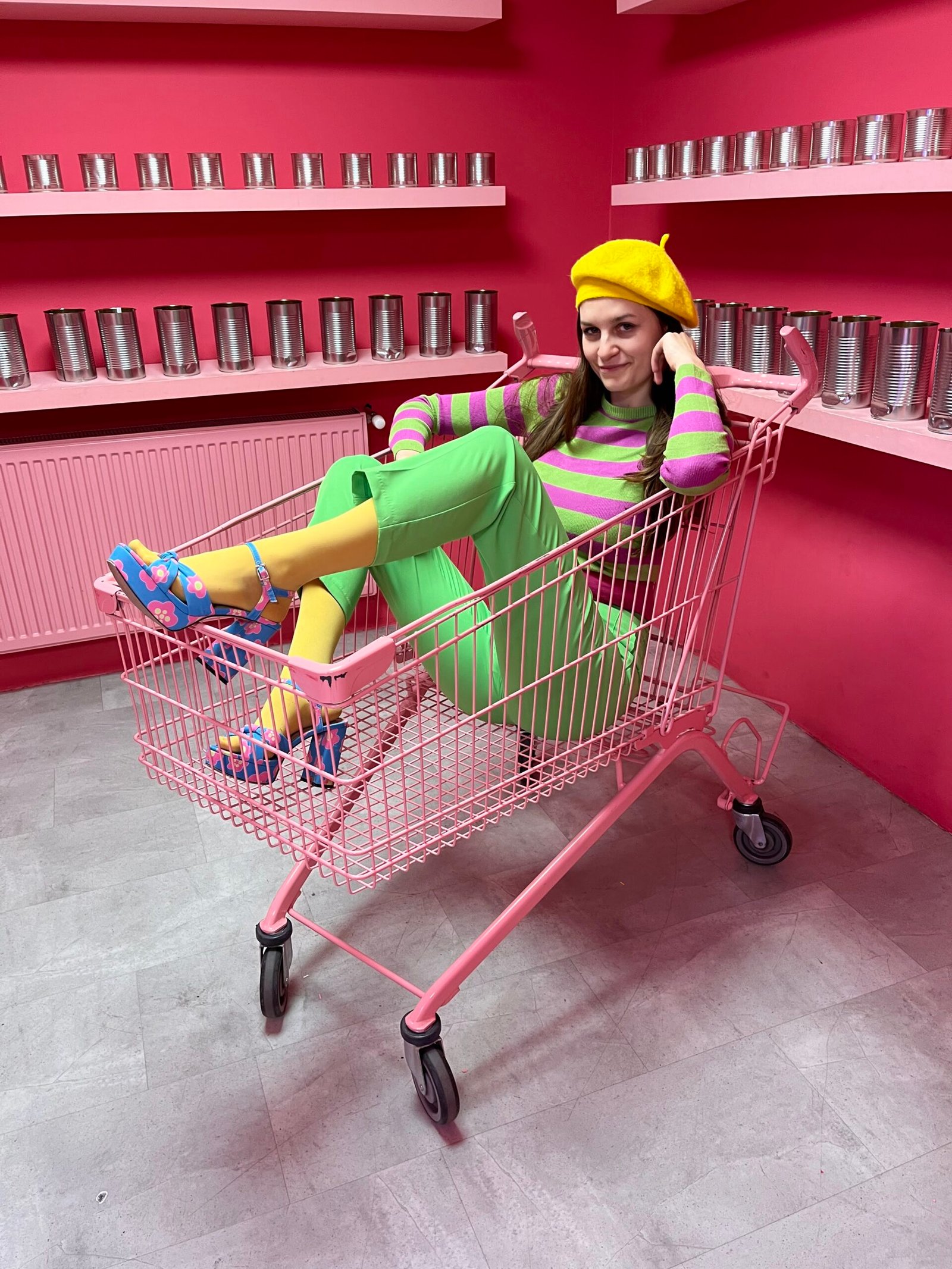 Marysia from Marysia's Colorful Closet sitting in a shopping cart in a colorful outfit and smiling