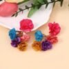 colorful floral earrings on the beige table, flowers next to them