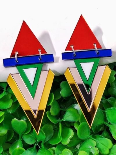 colorful geometric earrings on a white plate, plants in the background