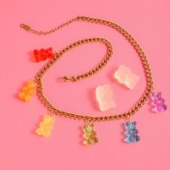 colorful gummy bear necklace rolled on the pink surface nect to white gummy bears