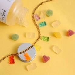 side view of colorful gummy bear necklace on the yellow background with real gummy bears next to it
