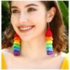 woman with brown hair and green eyes wearing colorful tassel earrings and smiling widely