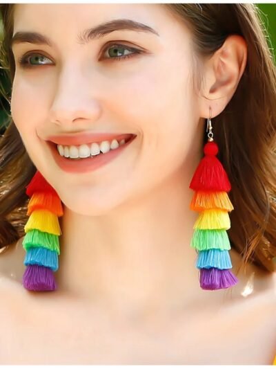 woman with brown hair and green eyes wearing colorful tassel earrings and smiling widely