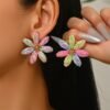 woman with dark brown hair wearing multicolored flower earrings