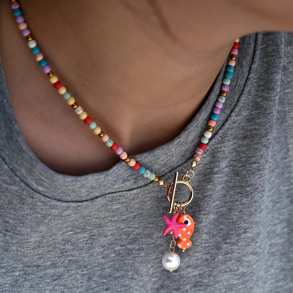 woman wearing colorful sea-inspired necklace on the grey shirt