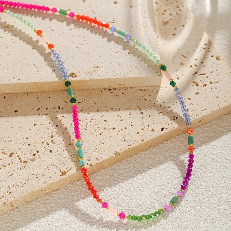 side view of multicolor beaded necklace on a beige backgorund