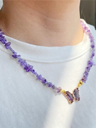 woman wearing purple necklace on a a white shirt